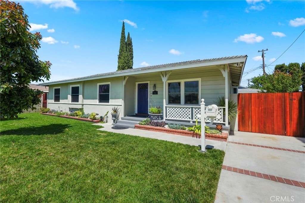 Single-story home on Kathy Ln, Garden Grove, CA, featuring white siding, a red fence, and a covered porch.