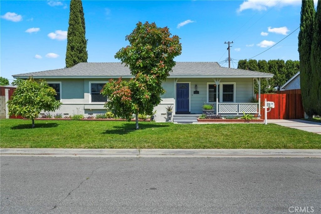 Single-story home on Kathy Ln, Garden Grove, CA, featuring a white fence, green lawn, and two large front trees.
