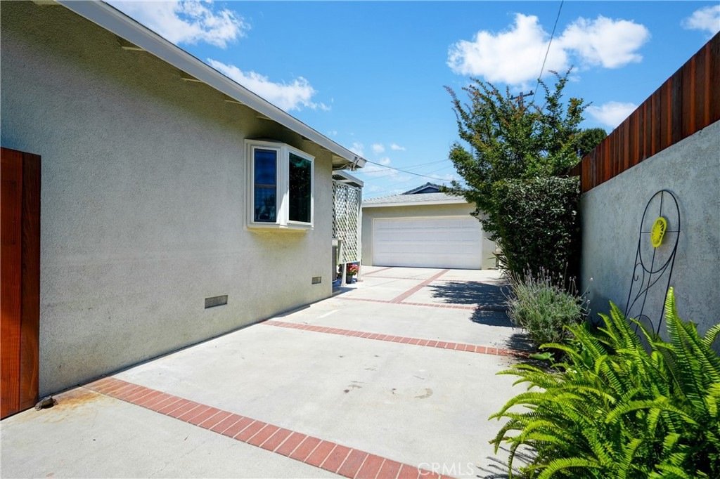 Driveway on Kathy Ln, Garden Grove, CA, with red brick edges, a wooden fence, and a garage.
