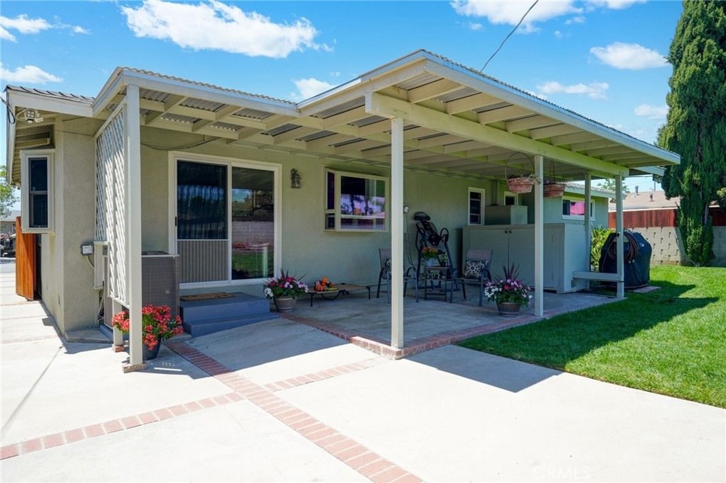 Covered patio on Kathy Ln, Garden Grove, CA, featuring wicker chairs, small table, and potted flowers.