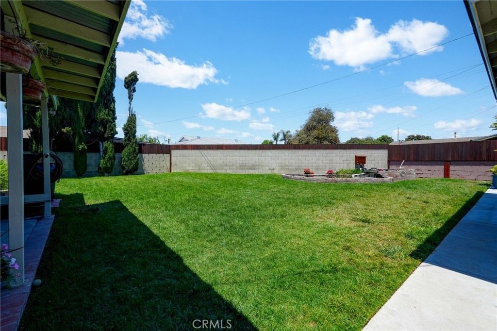 Spacious backyard on Kathy Ln, Garden Grove, CA, featuring a green lawn, brick wall, and minimalist landscaping.