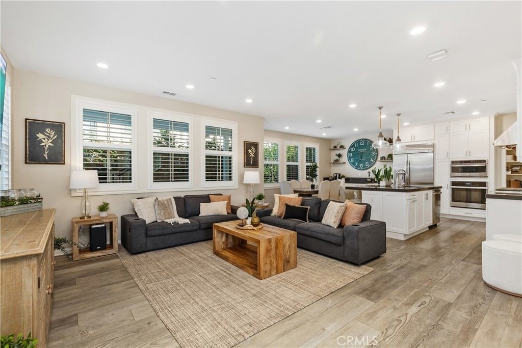 Living room and kitchen on Veraz Rd, Rancho Mission Viejo, CA, featuring gray sofas, a wooden coffee table, and a large wall clock.