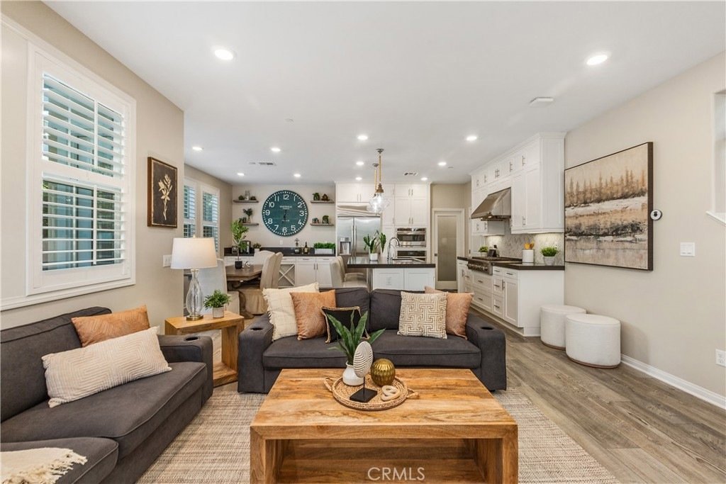 Modern living room on Veraz Rd, Rancho Mission Viejo, CA, featuring a dark gray couch, wooden coffee table, and open-concept kitchen.