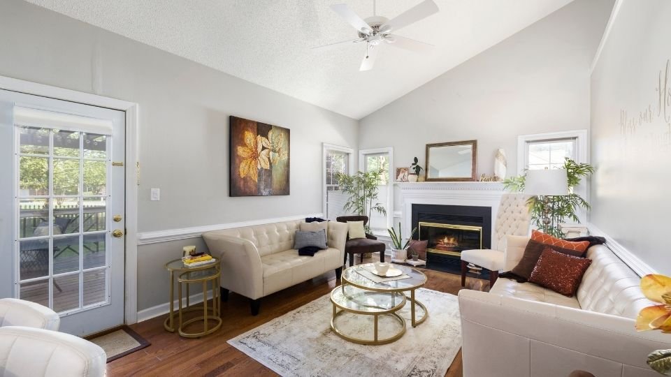 California living room with beige sofas, a glass coffee table, and a lit fireplace.