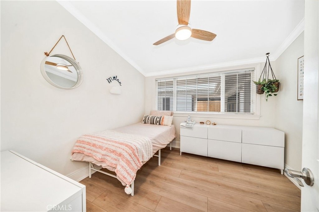 Bedroom on Hanover Dr, Costa Mesa, CA, with a pink-striped blanket, wood floor, wall mirror, and ceiling fan.