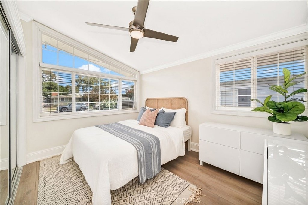 Bedroom on Hanover Dr, Costa Mesa, CA, with a double bed, white blankets, pastel pillows, and wood floors.