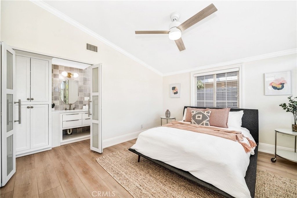 Bedroom on Hanover Dr, Costa Mesa, CA, with a white bed, patterned pillows, a ceiling fan, and a view into a bathroom.