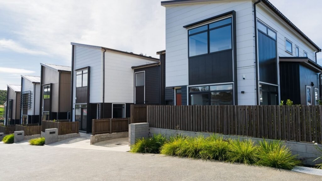Modern California townhouses with black and white facades, large windows, and wooden fences.
