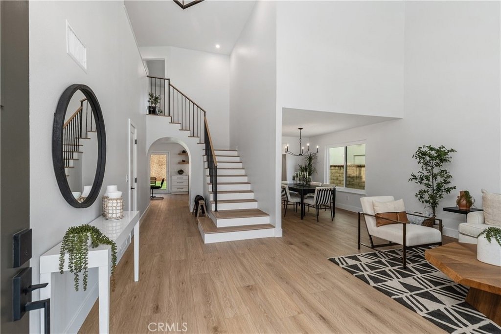 Bright California home on Cindy Ln in Lake Forest featuring light wood floors, a white staircase with black railings, and minimalist decor.